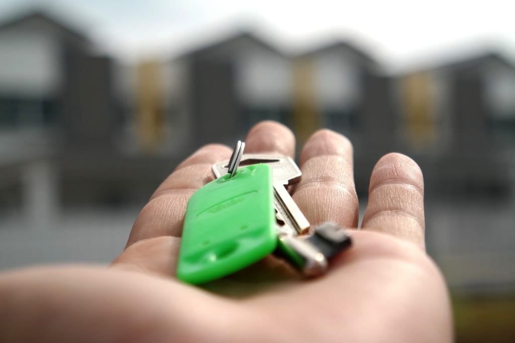 Hand with a set of house keys on a green keychain.