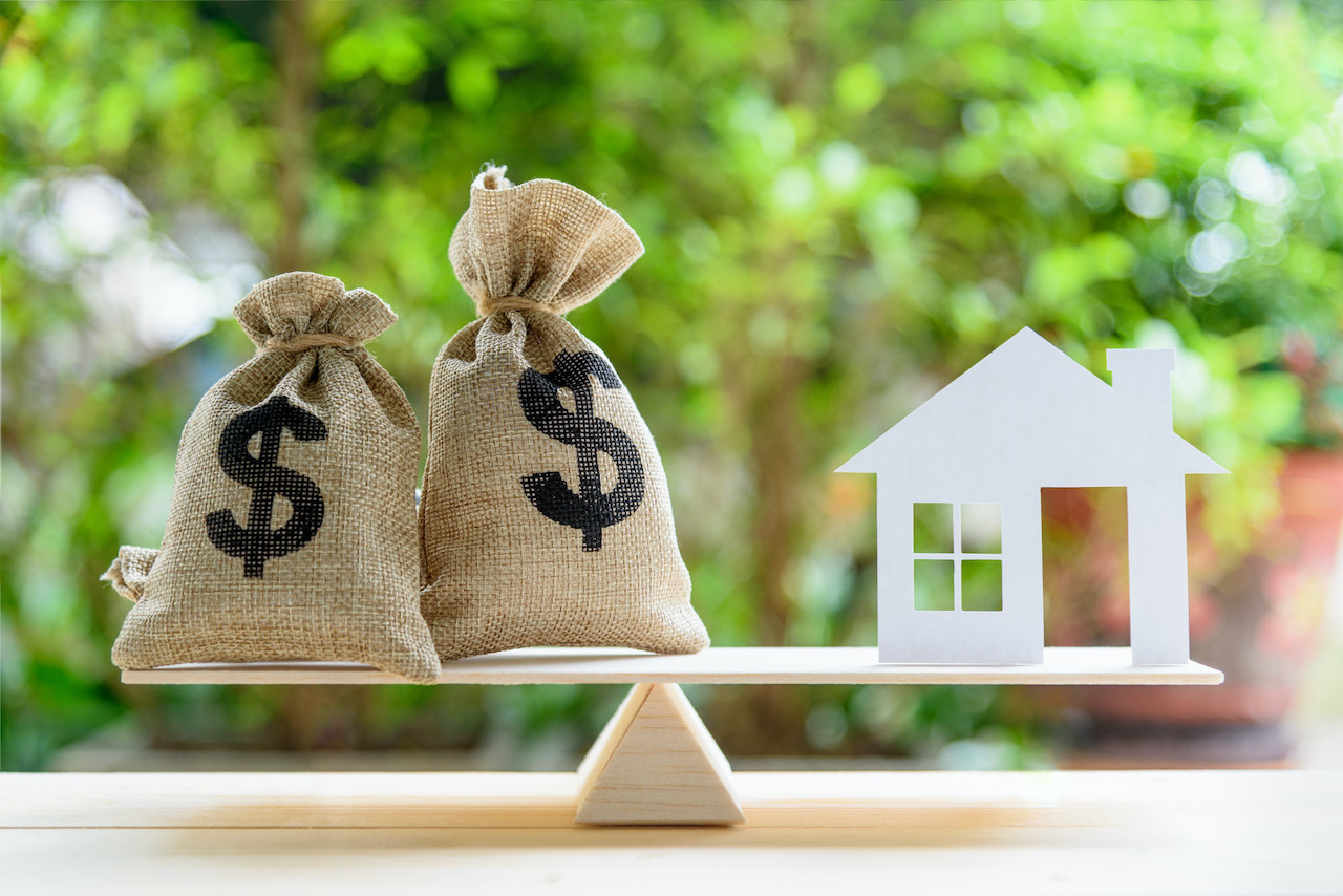 Weigh scale with 2 money bags and a mock-house