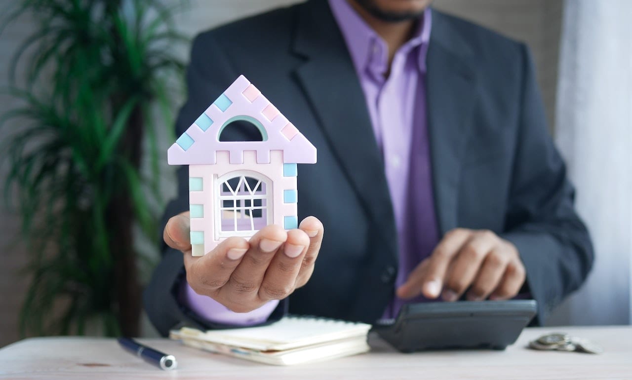 Person holding a small house indicating property purchase